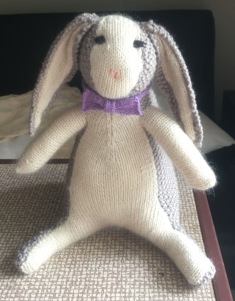 Grey and white knit rabbit with a purple bow-tie